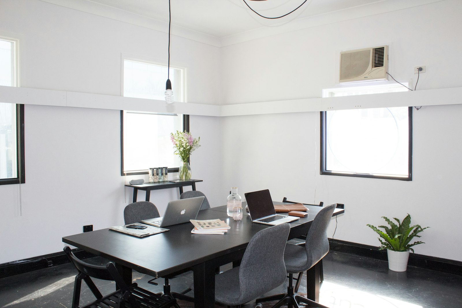 A bright studio meeting room with a long table and laptops